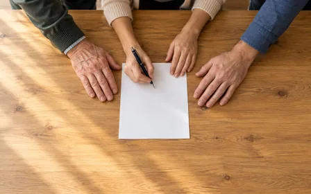 Adults' hands at a volunteer donor registration table.